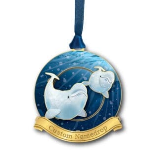 A gold Christmas ornament hanging from a blue cord featuring Beluga whales with a custom namedrop banner.