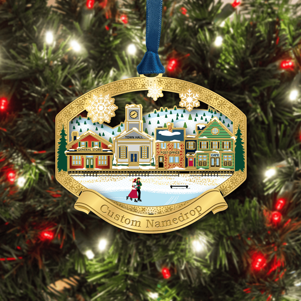 Custom namedrop ornament featuring a winter village with a general store, town hall, post office, and café, with ice skaters in the foreground, displayed on a decorated Christmas tree