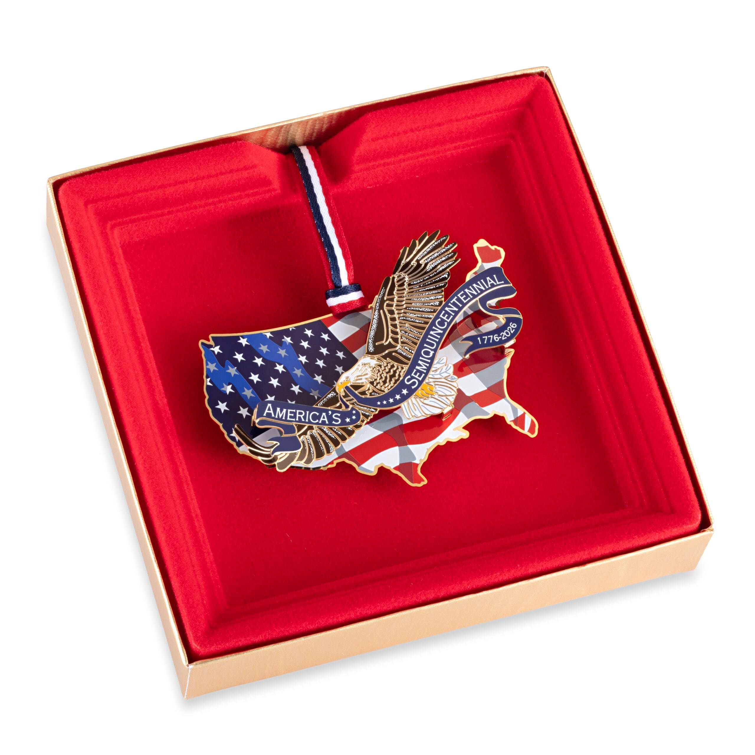America250 eagle ornament displayed inside a red velvet-lined presentation box, featuring a gold eagle over a U.S. map with American flag detailing and a patriotic ribbon.